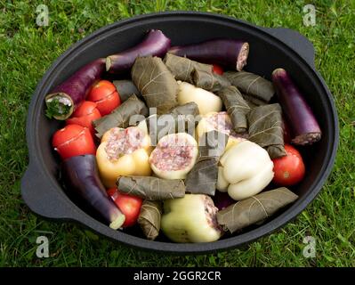 Peperoni, melanzane, pomodori e foglie d'uva riempiti con il ripieno di carne-riso per la cottura della dolma. Verdure farcite nella grande padella all'aperto. Colore Foto Stock