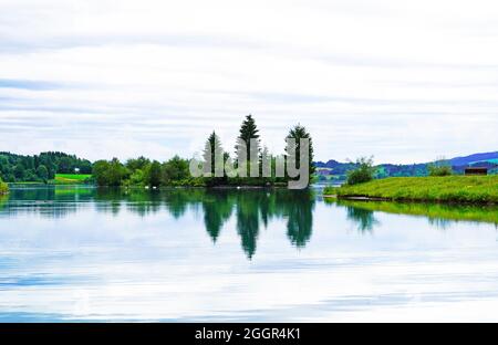 Lech Reservoir a Lechbruck am See. Vista sul lago con la natura circostante. Riflessione nell'acqua. Foto Stock