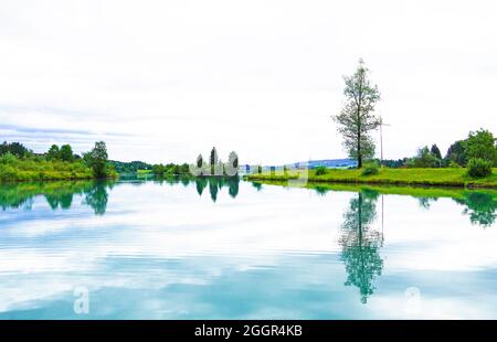 Lech Reservoir a Lechbruck am See. Vista sul lago con la natura circostante. Riflessione nell'acqua. Foto Stock