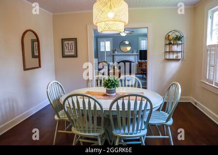 Una piccola sala da pranzo con un'illuminazione in rattan di tendenza e un tavolo da pranzo dipinto di blu Foto Stock