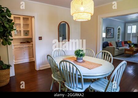 Una piccola sala da pranzo con un'illuminazione in rattan di tendenza e un tavolo da pranzo dipinto di blu Foto Stock