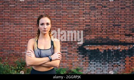 Sportswoman con le braccia incrociate in posa Foto Stock