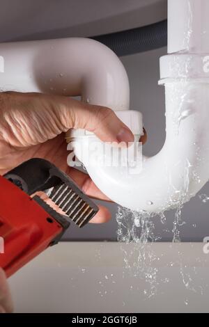 Perdita di acqua dal tubo di riparazione dell'idraulico. Fissaggio delle tubazioni Foto Stock