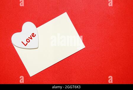 mockup giorno di vellentine con busta bianca e cuore su sfondo di carta rossa Foto Stock