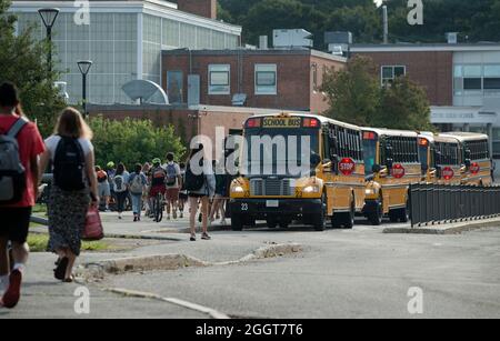 Primo giorno di scuola alla Lexington High School, Lexington, Massachusetts, USA. 31 agosto 2021. Lexington è una città con popolazione superiore a 33,000 abitanti, 10 km a nord-ovest di Boston. Più di 2,200 studenti sono iscritti per l'anno scolastico 2021-22. Tutti gli studenti, gli insegnanti e il personale sono attualmente tenuti a indossare una copertura o una maschera per il viso quando sono interni o non sono in grado di distanza sociale. La foto mostra gli studenti e gli autobus della scuola al mattino all'ingresso principale della scuola. Foto Stock