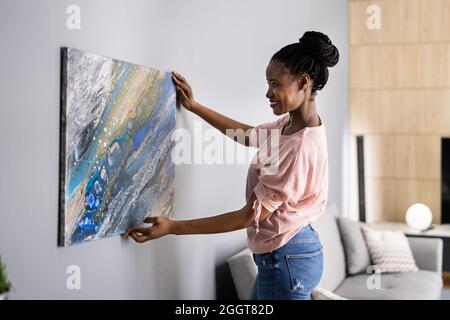 Donna sorridente che appica la pittura o l'immagine all'interno Foto Stock