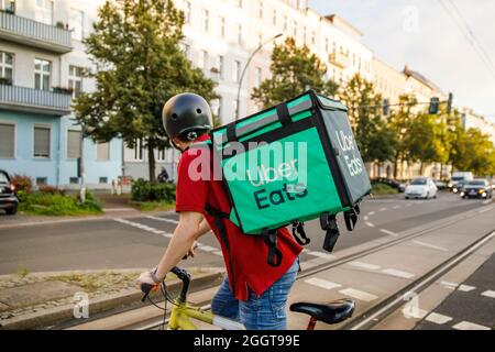 Berlino, Germania. 2 settembre 2021. Silvan, un autista per il servizio di consegna di cibo Uber mangia, si sposta in bicicletta con una scatola di trasporto sul retro su una strada nel quartiere Prenzlauer Berg di Berlino. Credit: Carsten Koall/dpa/Alamy Live News Foto Stock