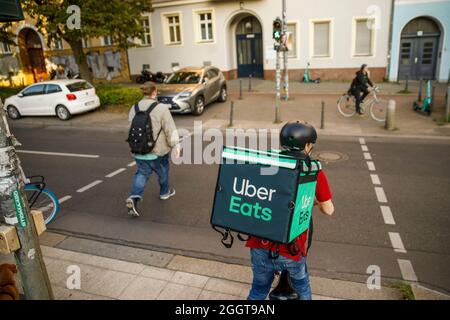 Berlino, Germania. 2 settembre 2021. Silvan, un autista per il servizio di consegna di cibo Uber mangia, si sposta in bicicletta con una scatola di trasporto sul retro su una strada nel quartiere Prenzlauer Berg di Berlino. Credit: Carsten Koall/dpa/Alamy Live News Foto Stock