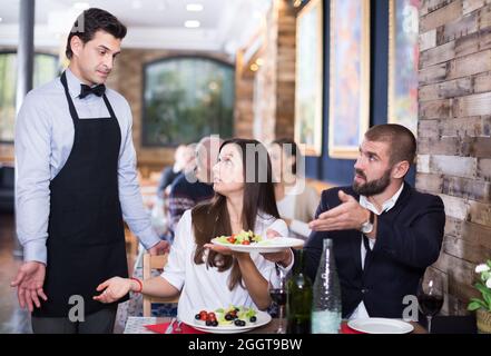 Adulto Giovane esprimere insoddisfazione con cameriere circa il cibo Foto Stock