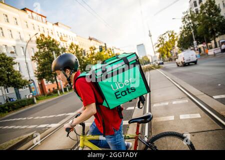 Berlino, Germania. 2 settembre 2021. Silvan, un autista per il servizio di consegna di cibo Uber mangia, si sposta in bicicletta con una scatola di trasporto sul retro su una strada nel quartiere Prenzlauer Berg di Berlino. Credit: Carsten Koall/dpa/Alamy Live News Foto Stock