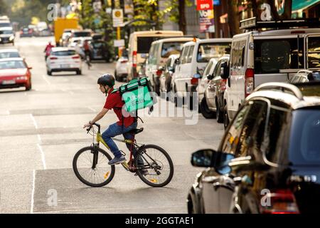 Berlino, Germania. 2 settembre 2021. Silvan, un autista per il servizio di consegna di cibo Uber mangia, si sposta in bicicletta con una scatola di trasporto sul retro su una strada nel quartiere Friedrichshain di Berlino. Credit: Carsten Koall/dpa/Alamy Live News Foto Stock