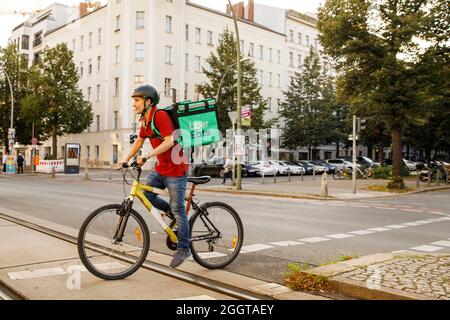 Berlino, Germania. 2 settembre 2021. Silvan, un autista per il servizio di consegna di cibo Uber mangia, si sposta in bicicletta con una scatola di trasporto sul retro su una strada nel quartiere Prenzlauer Berg di Berlino. Credit: Carsten Koall/dpa/Alamy Live News Foto Stock