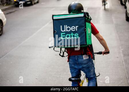 Berlino, Germania. 2 settembre 2021. Silvan, un autista per il servizio di consegna di cibo Uber mangia, si sposta in bicicletta con una scatola di trasporto sul retro su una strada nel quartiere Friedrichshain di Berlino. Credit: Carsten Koall/dpa/Alamy Live News Foto Stock