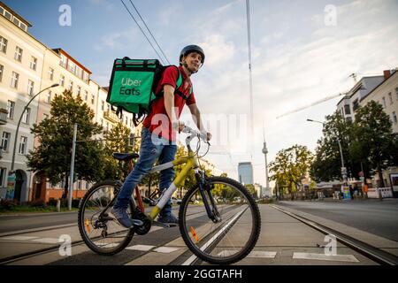 Berlino, Germania. 2 settembre 2021. Silvan, un autista per il servizio di consegna di cibo Uber mangia, si sposta in bicicletta con una scatola di trasporto sul retro su una strada nel quartiere Prenzlauer Berg di Berlino. Credit: Carsten Koall/dpa/Alamy Live News Foto Stock