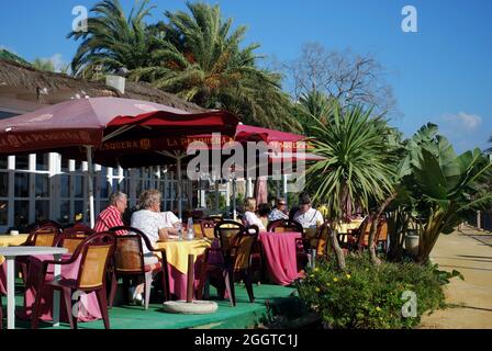 I turisti in un momento di relax a un caffè lungo la passeggiata accanto a Daitona beach, Marbella, Costa del Sol, provincia di Malaga, Spagna. Foto Stock