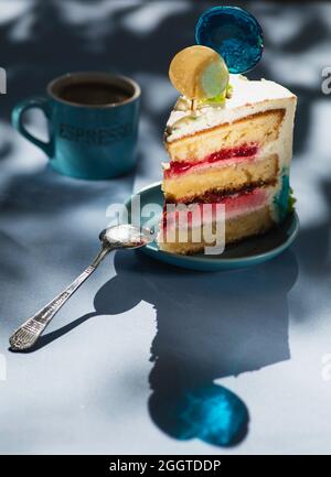 Piatto con fetta di gustosa torta fatta in casa sul tavolo, torta al lampone. Colourful lollipop swirl su bastone di legno Foto Stock