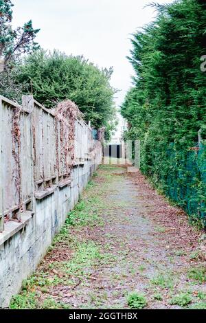 Passerella stretta / percorso tra recinzioni giardino di case. Foto Stock