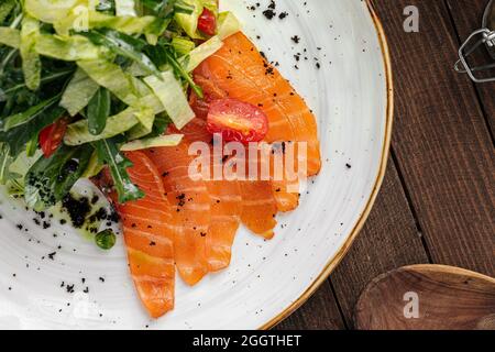Piatto di salmone affettato salato e insalata verde Foto Stock