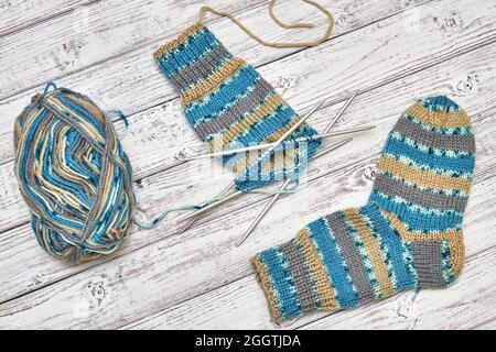 Lavorazione a maglia di calze per bambini su un fondo di legno chiaro Foto Stock