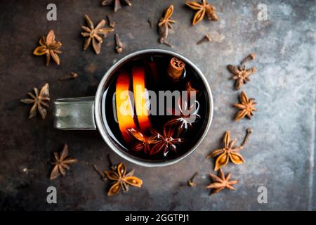 Vino rosso brulé in tazza metallica su fondo rustico grigio. Messa a fuoco selettiva. Profondità di campo ridotta. Foto Stock