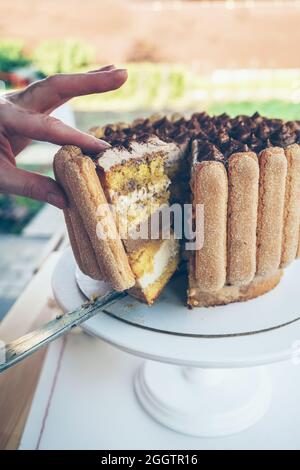 vista ravvicinata delle mani dei woman che ottengono fetta di torta di tiramisù appena tagliata Foto Stock