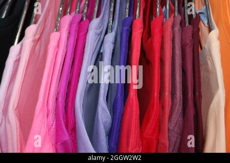 magliette colorate appese ad appendiabiti con gamme di colori Foto Stock