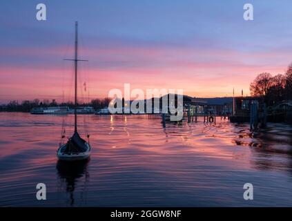 Emozionante tramonto invernale sul Lago maggiore con barca a vela in primo piano.Arona, Piemonte, Italia. Foto Stock
