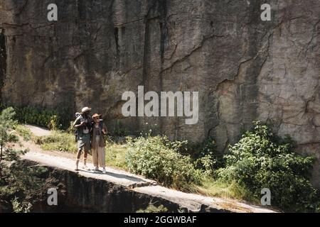 Coppia senior interrazziale con zaini che camminano sul sentiero vicino alla scogliera Foto Stock