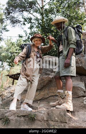Escursionisti anziani interrazziali che tengono le mani sulle pietre nella foresta Foto Stock
