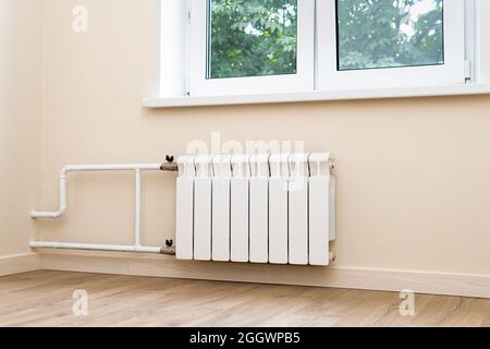 Moderno radiatore ad acqua collegato alla parete sotto la finestra Foto Stock