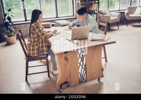 Foto a grandezza naturale di due studenti universitari concentrati che si apprestano a preparare un quaderno di scrittura per gli esami di lavoro Foto Stock