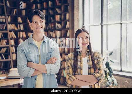 Foto di due sorridenti studenti universitari sorridenti e premurosi, con le braccia ripiegate, sembrano pensarci di lato Foto Stock