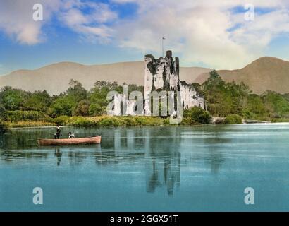 Una vista dei primi del 20 ° secolo di un pescatore sulla Lough Leane, vicino al Castello di Ross, un poi rovinato e cresciuto 15 ° secolo torre casa e tenere nel Killarney National Park, County Kerry, Irlanda. Foto Stock