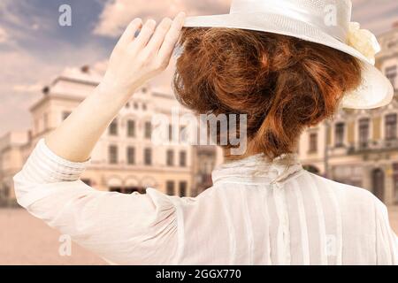 Immagine in stile retrò di donna in un cappello vittoriano guardando la strada della città in Europa. Filtro Seppia. Foto Stock