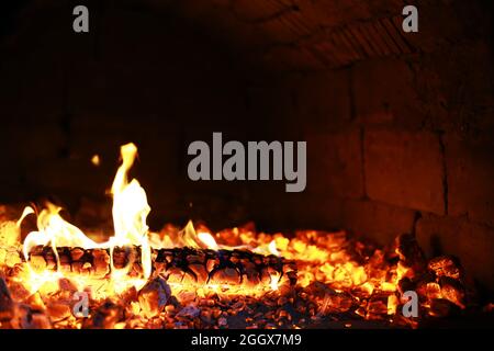 Scintille calde rosse che bruciano volano dal fuoco grande. Bel sfondo astratto sul tema del fuoco. Carboni brucianti, particelle infiammate che volano contro la colpa Foto Stock
