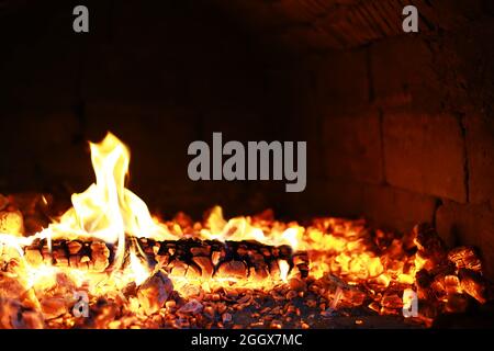 Scintille calde rosse che bruciano volano dal fuoco grande. Bel sfondo astratto sul tema del fuoco. Carboni brucianti, particelle infiammate che volano contro la colpa Foto Stock