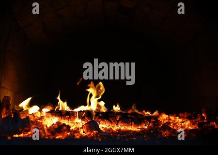 Scintille calde rosse che bruciano volano dal fuoco grande. Bel sfondo astratto sul tema del fuoco. Carboni brucianti, particelle infiammate che volano contro la colpa Foto Stock