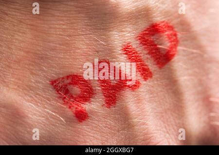 Timbro con inchiostro rosso con la parola pagata sul retro di una mano Foto Stock