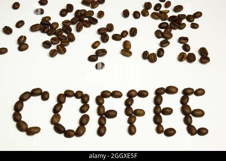 La parola CAFFÈ è disposta su uno sfondo bianco con chicchi di caffè. I chicchi di caffè sono sparsi sulla parte superiore Foto Stock