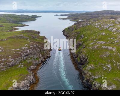 Vista aerea dal drone di barca da pesca che naviga tra il canale tra Little Bernera e Great Bernera sull'Isola di Lewis, Ebridi esterne, Scozia, U. Foto Stock