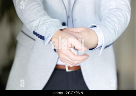 Primo piano immagine di una moda le mani di un giovane uomo d'affari, bel modello uomo in costume casual. Indossare il gilet nella gabbia, jeans neri e maglietta blu. Foto di alta qualità Foto Stock