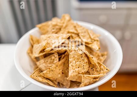 Macro closeup di mais bianco giallo gratis tortilla chips fatto con manioca in piatto piatto che mostra texture con bokeh sfondo della cucina casa camera Foto Stock