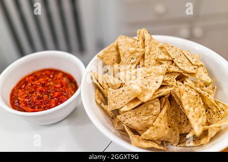 Primo piano di salsa rossa chunky e mais free bianco giallo tortilla chips fatto con manioca in piatto piatto piatto in casa cucina Foto Stock