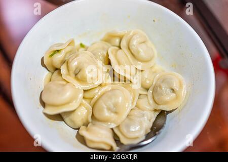 Primo piano macro di gnocchi tradizionali russi pelmeni con ripieno di carne o formaggio o patate e pancetta ripieno in ciotola Foto Stock