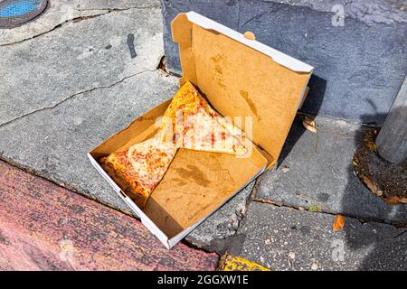 Lasciato dietro gettato via le fette scartate di pizza di formaggio in contenitore scatola sul marciapiede strada fuori fuori fuori fuori fuori rifiuti alimentari a Key West, Florida Foto Stock