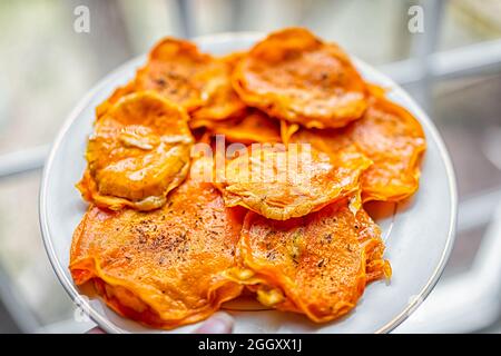 Macro closeup di donna che tiene piatto bianco con zucca butternut squash crudo ravioli ripieni disidratati alimenti italiani con fette, oliva extra vergine Foto Stock