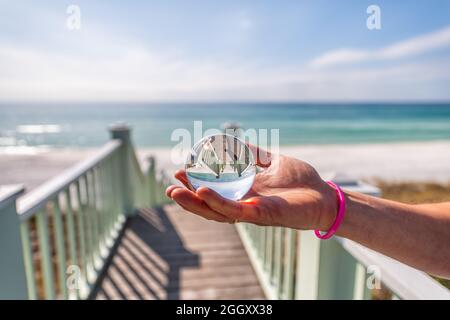 Mare, Florida con mano uomo che tiene la palla di cristallo di lente sfera di vetro con riflesso di verde padiglione di legno gradini scale architettura di scala bea Foto Stock