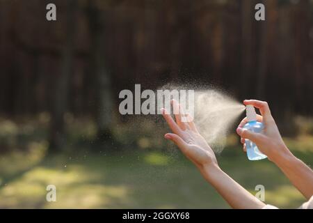 Womans mano che preme alcool Spray nella natura per pulire la sua mano. Alcool Spray è molto importante nella vita quotidiana. mosquito repellente o antisettico. Foto Stock