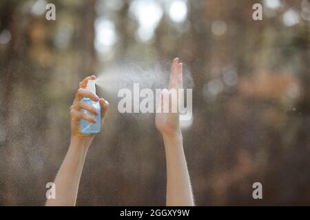 Womans mano che preme alcool Spray nella natura per pulire la sua mano. Alcool Spray è molto importante nella vita quotidiana. mosquito repellente o antisettico. Foto Stock
