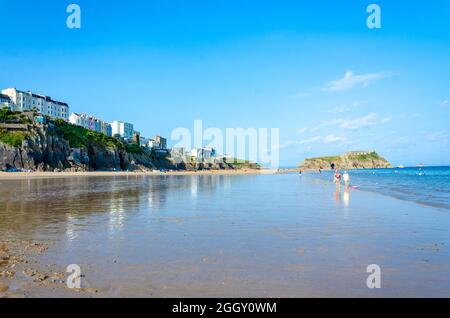Una vista lungo la South Beach a Tenby in Galles, Regno Unito con l'Isola di St Catherine sulla destra ed edifici colorati sull'Esplanade sulla sinistra. Foto Stock